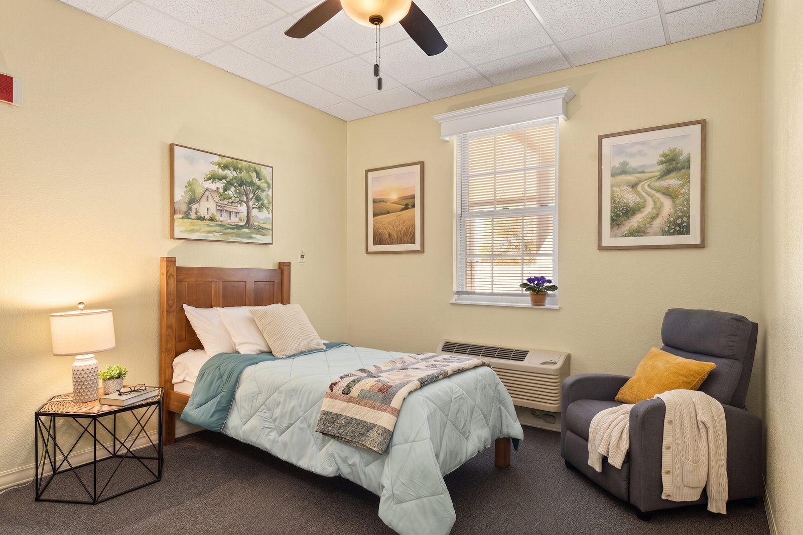 Private furnished suite at Savoy Place with a quilt on the bed, a reading chair, and warm lamplight